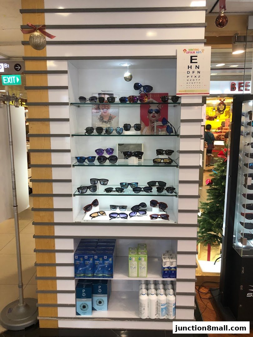 A display shelf in an optical shop showcasing sunglasses, contact lenses, and eye care products.
