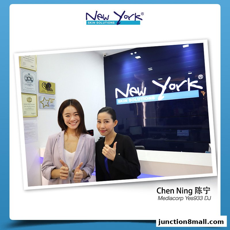 Two women giving thumbs up in front of a New York Skin Solutions branded reception area.