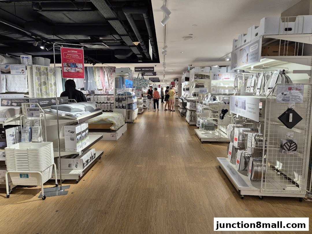 Interior view of a NITORI store showcasing bedding, home decor, and kitchenware with shoppers browsing.