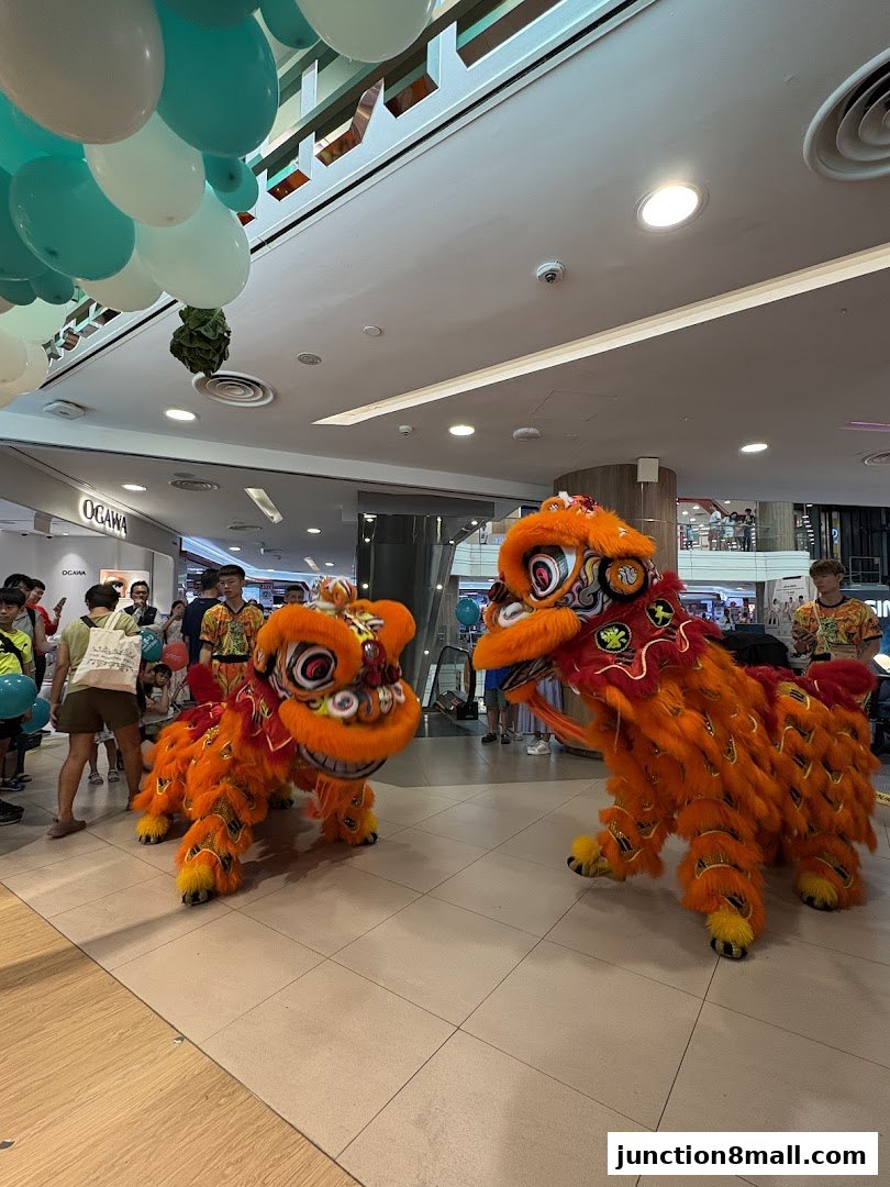 Lion dance performance with orange lions and people watching in a shopping mall.