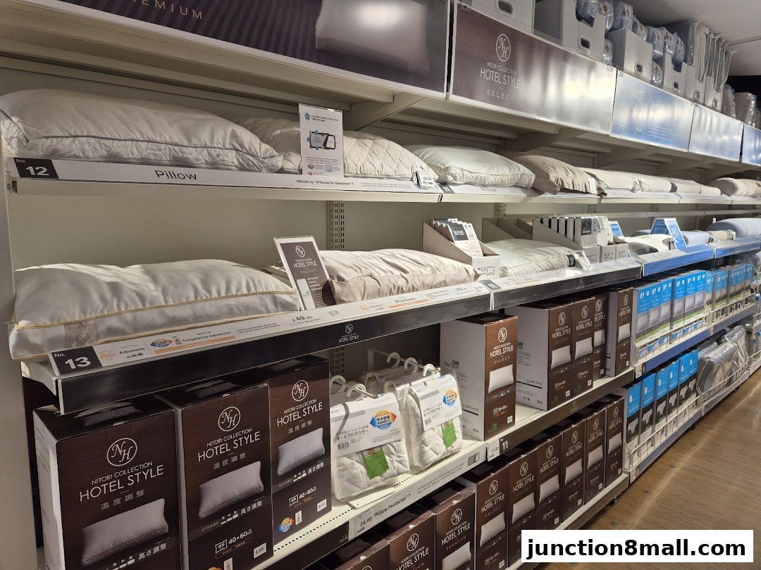 Shelves stocked with various pillows and bedding products, featuring NITORI HOTEL STYLE collection.