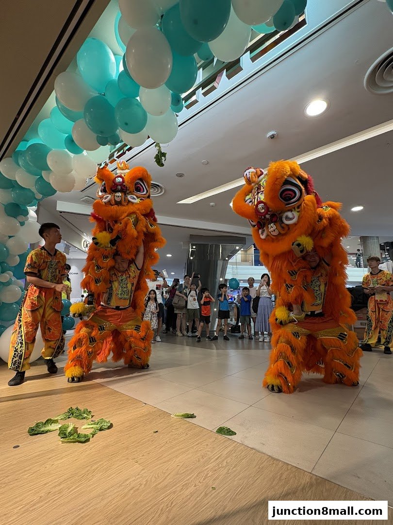 Lion dance performance with performers in orange costumes and a crowd watching.