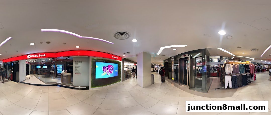 A panoramic view of a shopping mall corridor featuring an OCBC Bank branch and clothing displays.