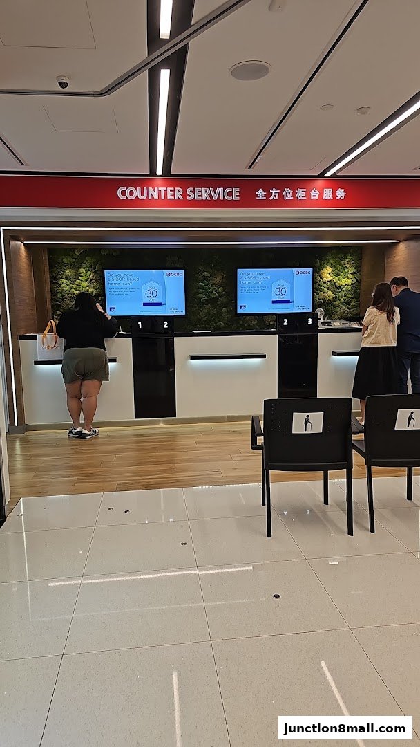 Customers at the counter service of OCBC Bank with digital displays showing loan information.