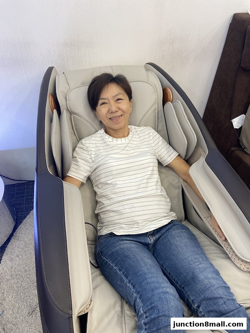 A woman smiles while relaxing in a modern massage chair at OGAWA.