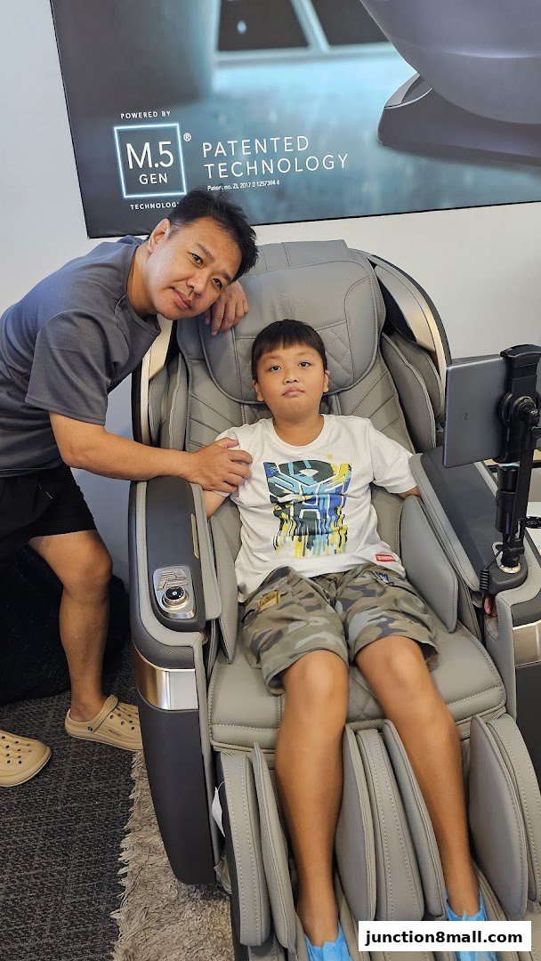 A father and son are posing in a massage chair with patented technology.