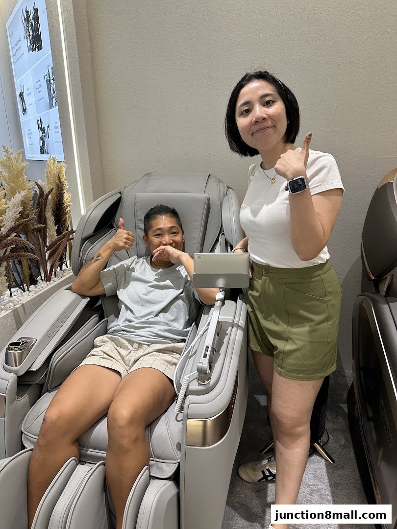 Two smiling people give thumbs up while testing a massage chair at OGAWA Junction 8.