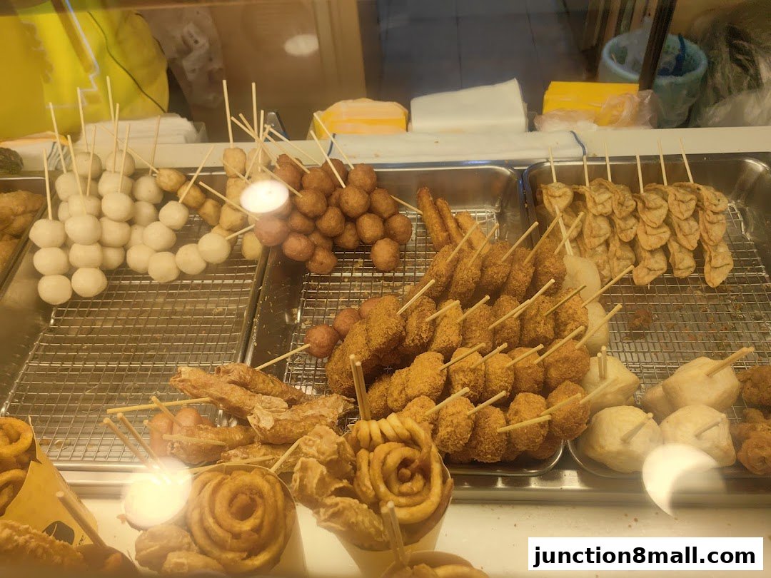 A display of various fried snacks on skewers, including fish balls, sausages, and crispy items.