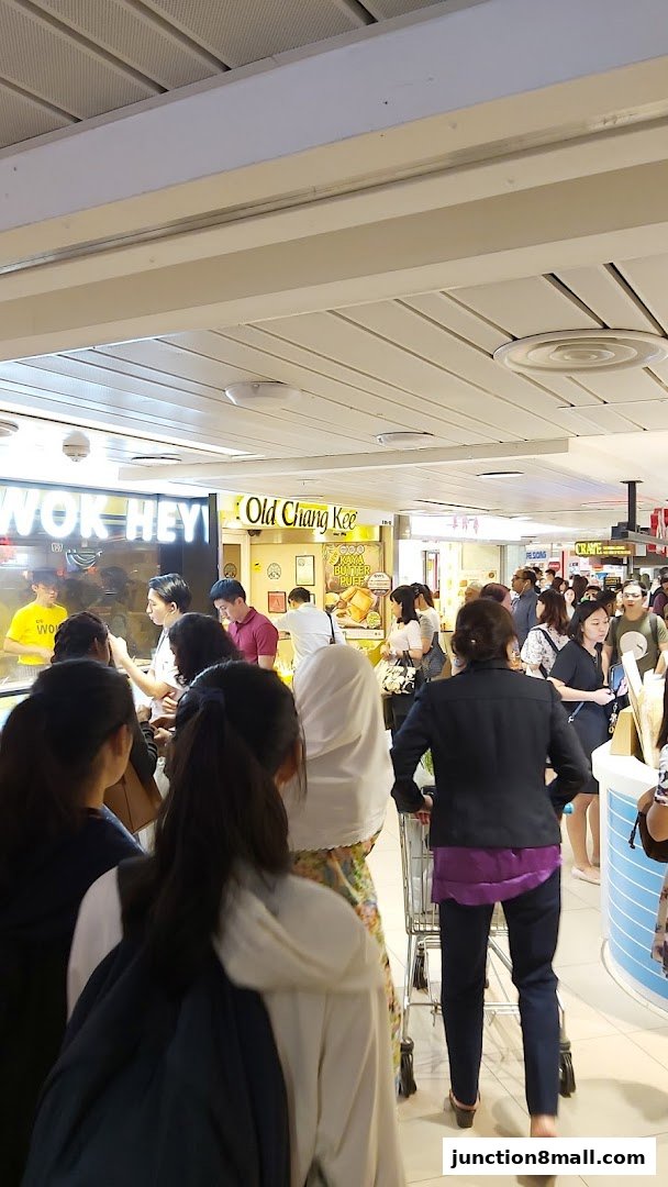 A busy Old Chang Kee shop with customers queuing and staff serving food.