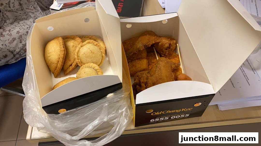 Two open boxes of Old Chang Kee food, one with pastries and the other with fried chicken.
