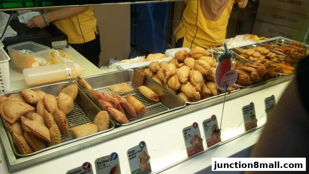A display of various fried snacks and pastries at Old Chang Kee, with prices visible.