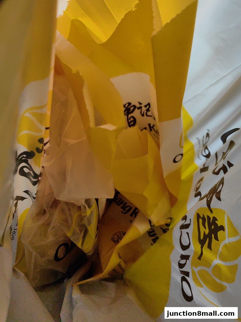 A close-up view inside a yellow Old Chang Kee paper bag filled with food items.