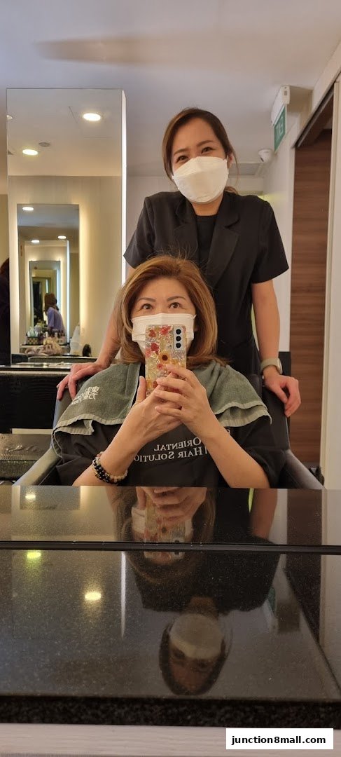A woman is getting her hair done by a stylist at Oriental Hair Solutions.