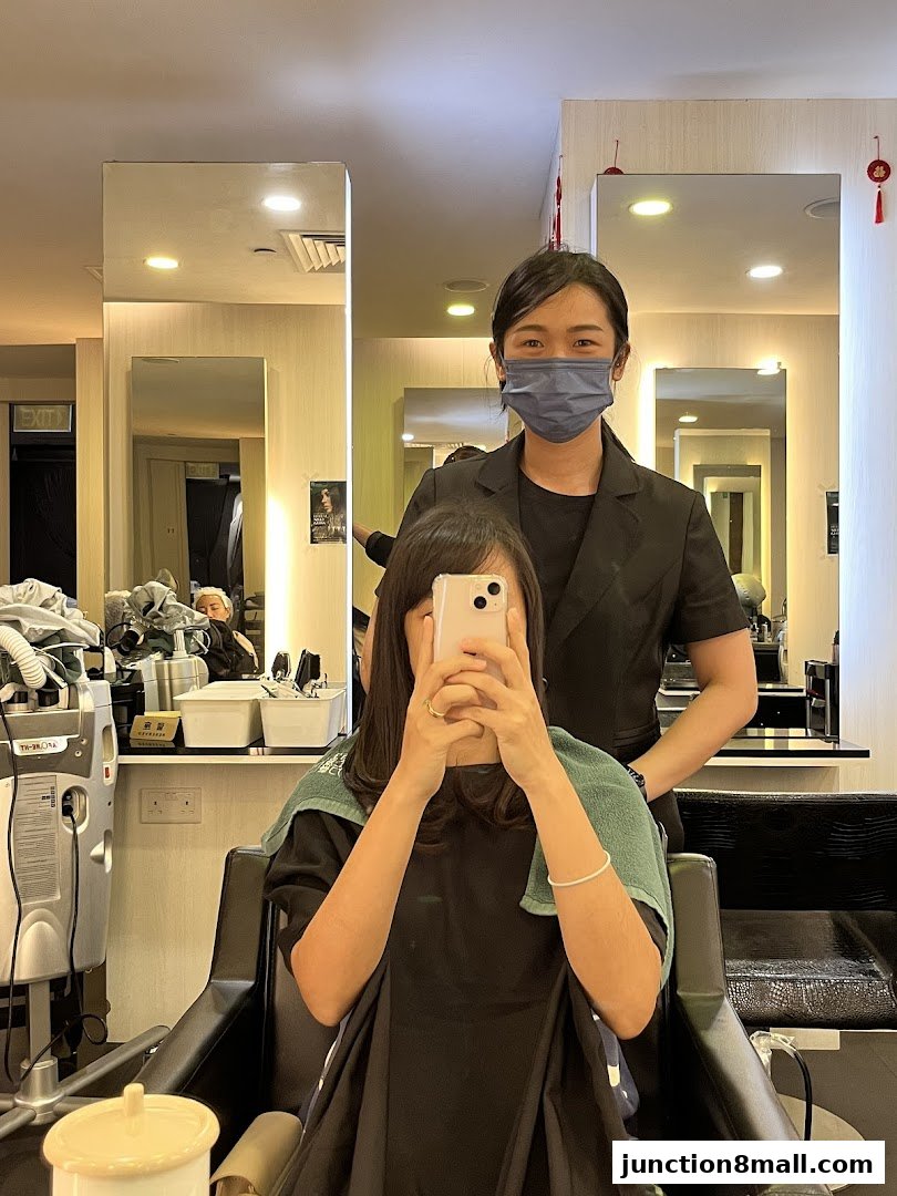 A hairstylist stands behind a client seated in a salon chair, both masked.