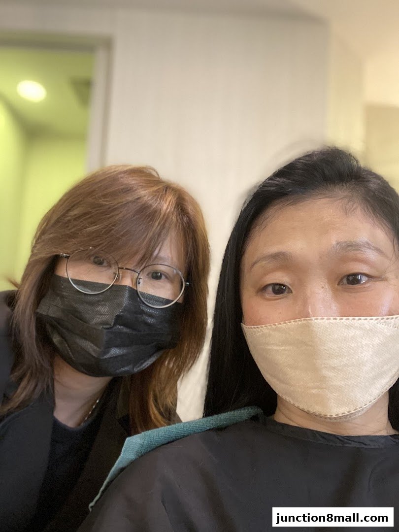 Two women wearing masks, one with brown hair and glasses, the other with black hair.