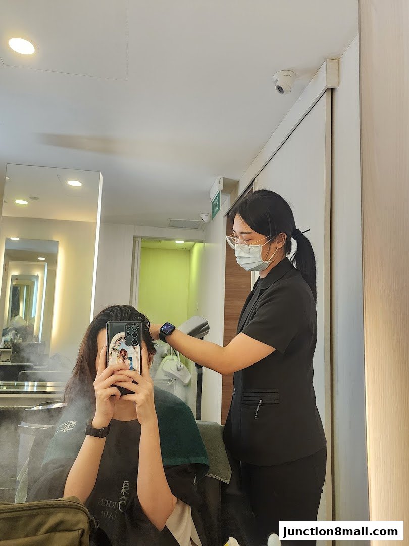 A stylist uses a steamer on a client's hair in a salon setting.