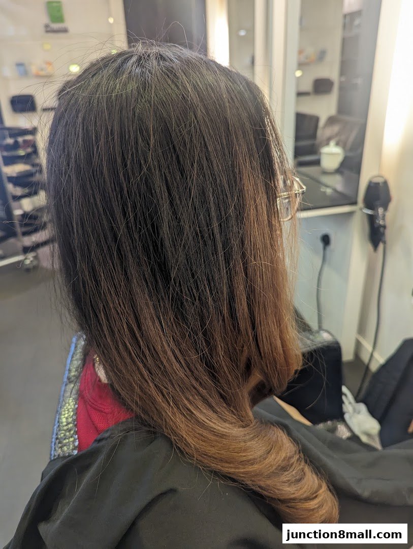 A person's long, brown hair styled with a curl, seen from behind in a salon.