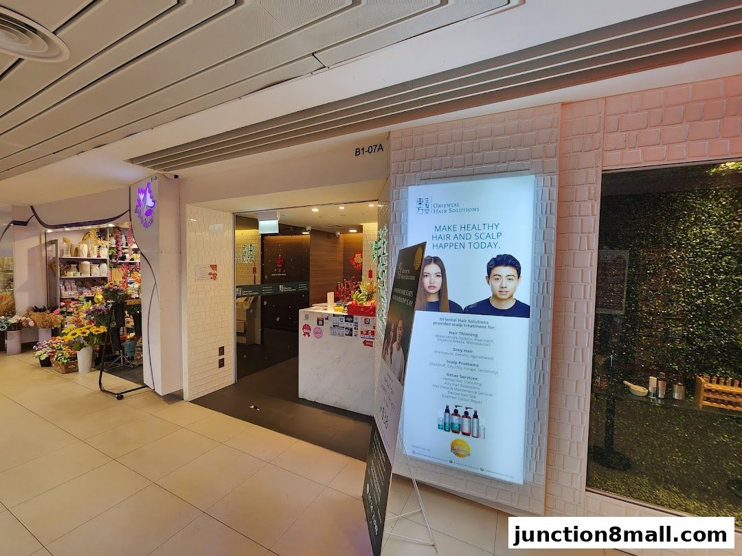 The entrance to Oriental Hair Solutions, featuring a lit display board with services and product images.