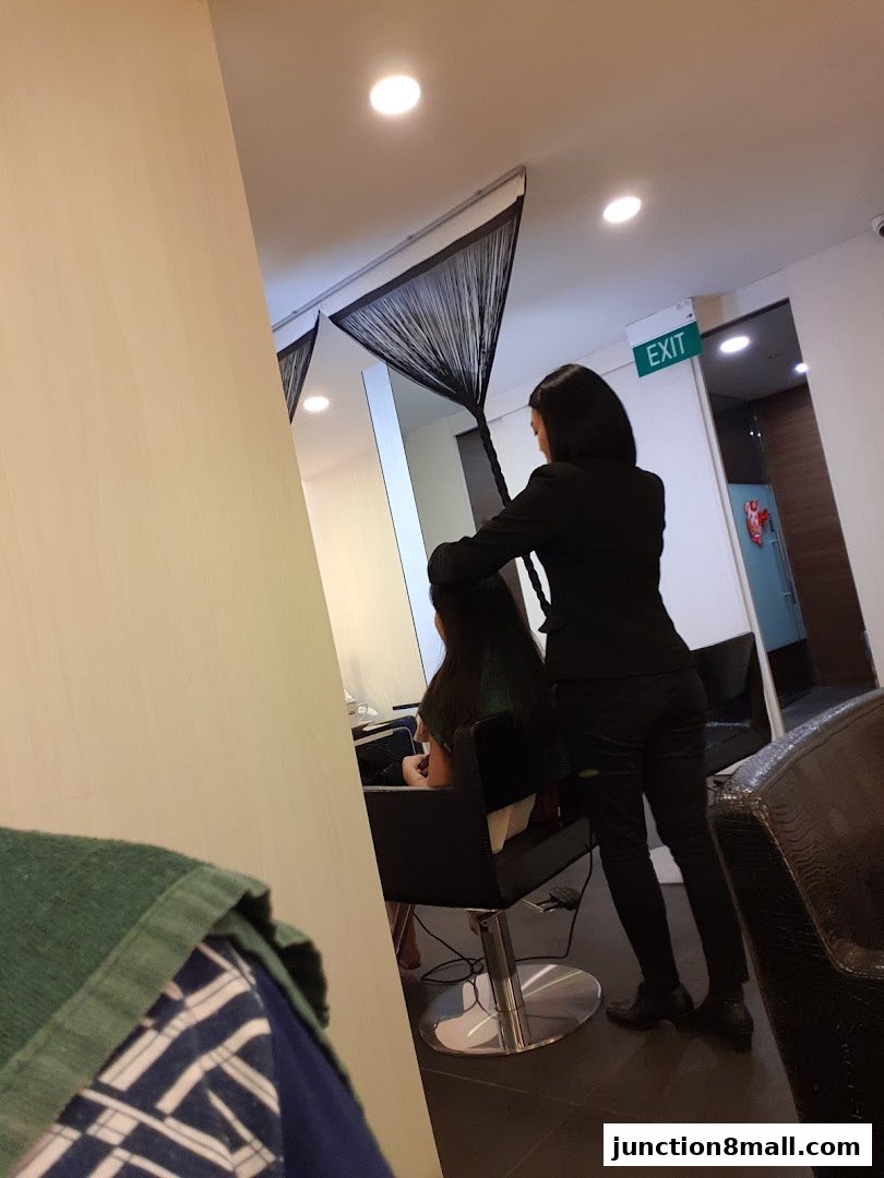 A hairstylist works on a client's hair in a modern salon setting.
