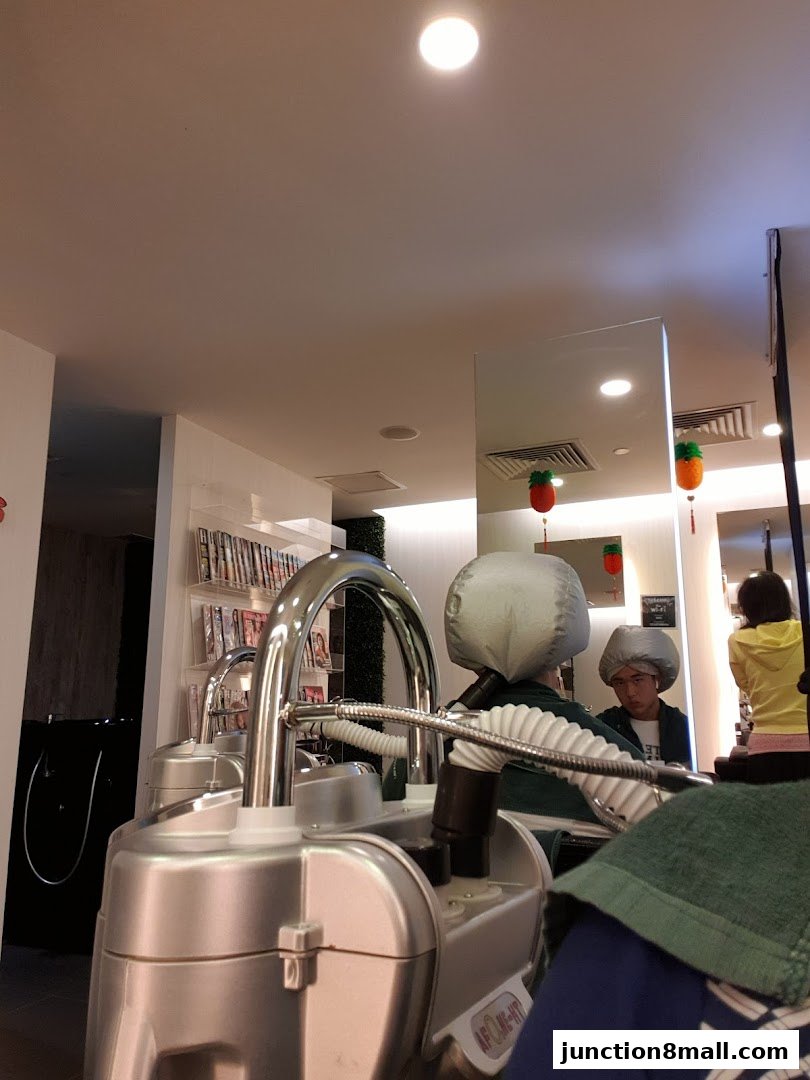 Interior of a hair salon with customers wearing hair dryers and styling equipment.