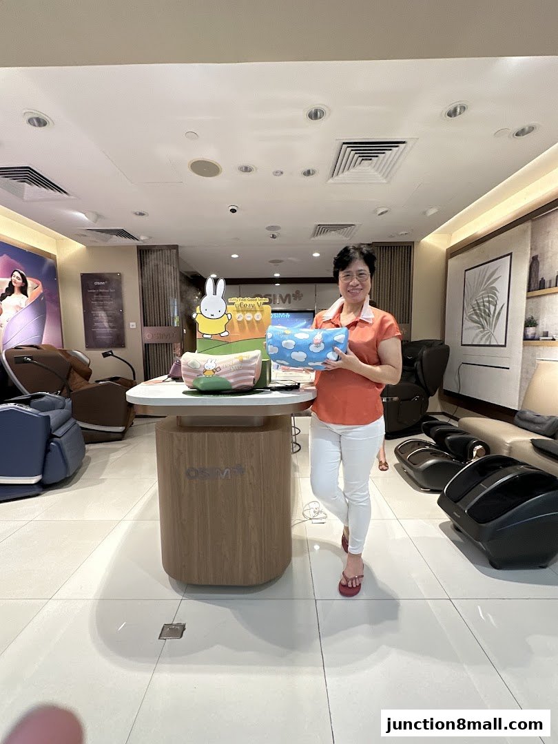 A woman stands in an OSIM store holding a blue pillow with clouds and bunnies.