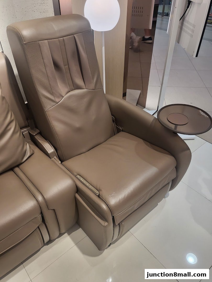 A close-up view of a luxurious, beige leather massage chair with a side tray.