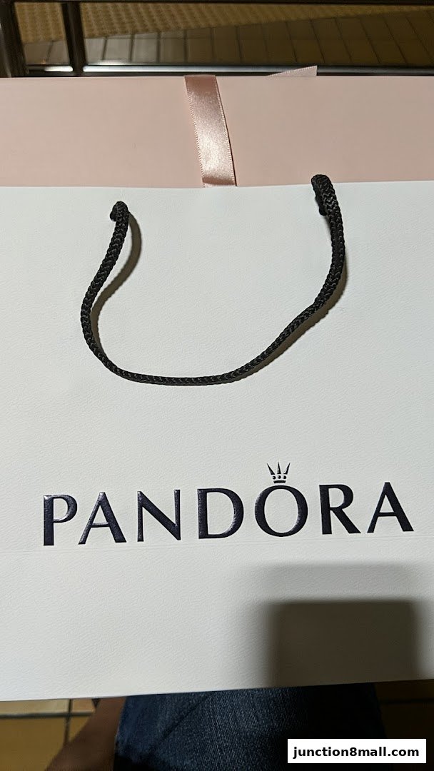 A white shopping bag with the Pandora logo and a pink ribbon detail.