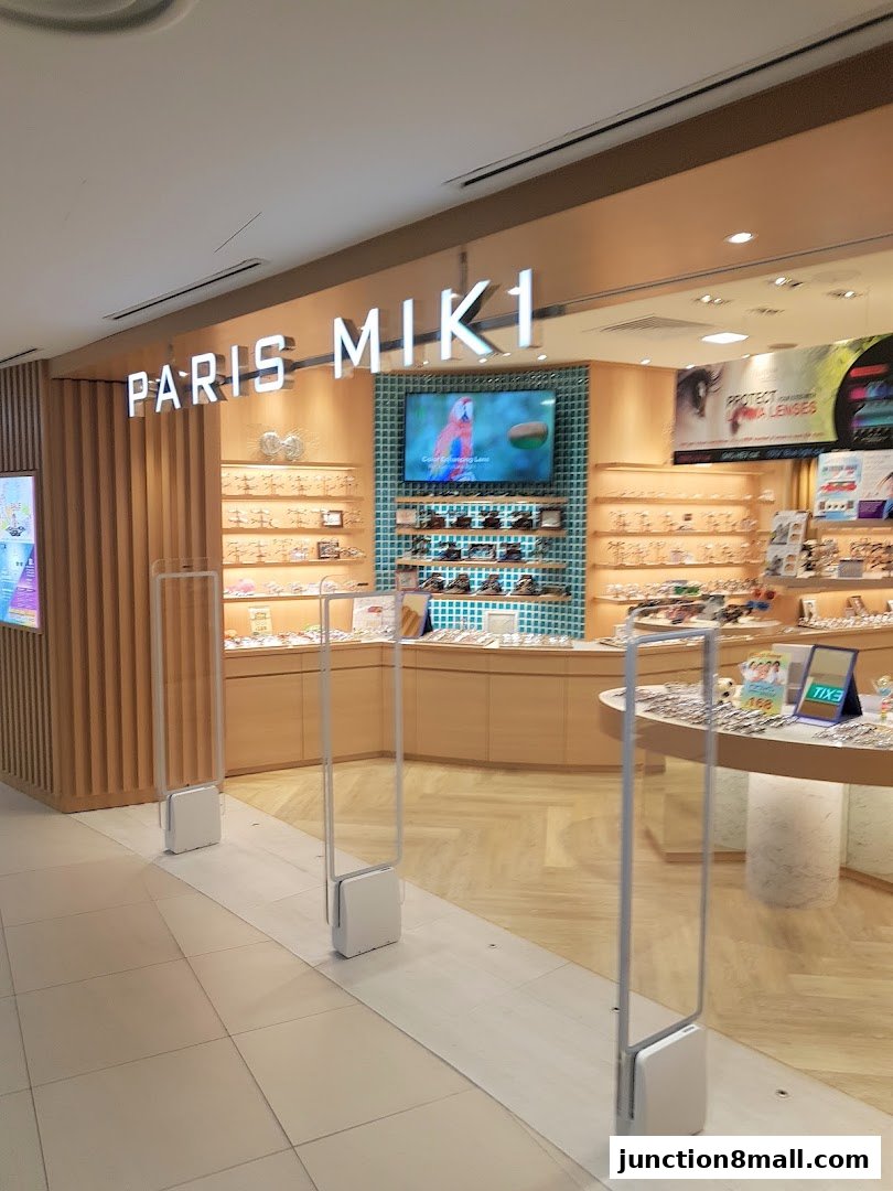 The entrance of Paris Miki, an optician shop, displaying various eyewear and eye care services.