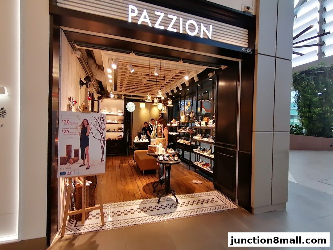 The entrance of PAZZION Junction 8 shoe store, showcasing stylish footwear and a promotional poster.