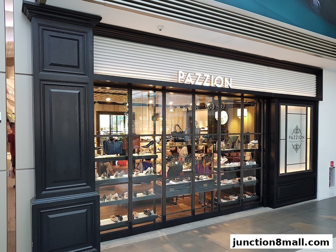 The PAZZION Junction 8 shoe store features a stylish black facade with a large glass display showcasing various footwear.