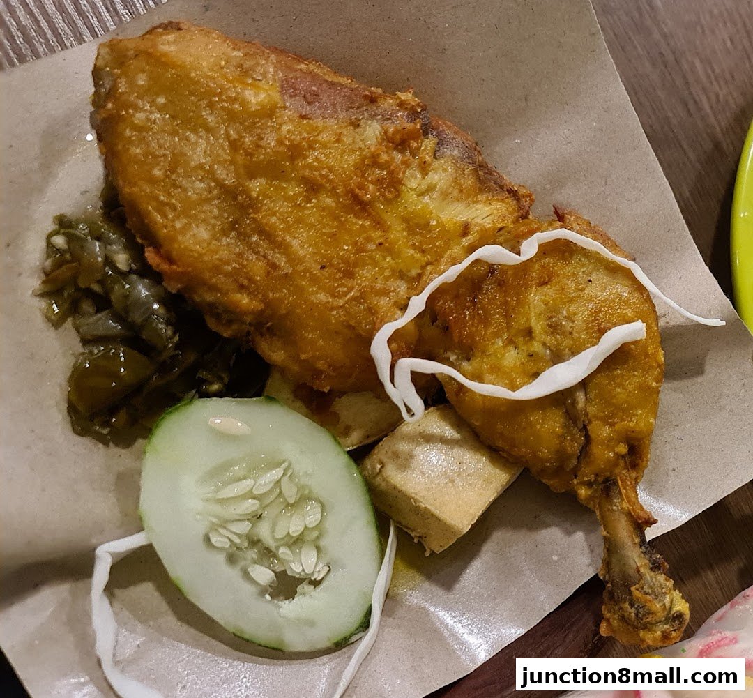 A close-up of a crispy fried chicken dish with cucumber, tofu, and chili.