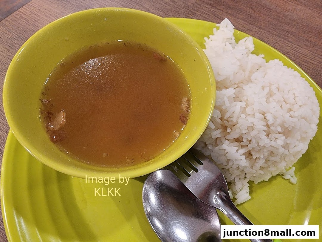 A close-up of a bowl of soup and a serving of rice on a bright green plate.