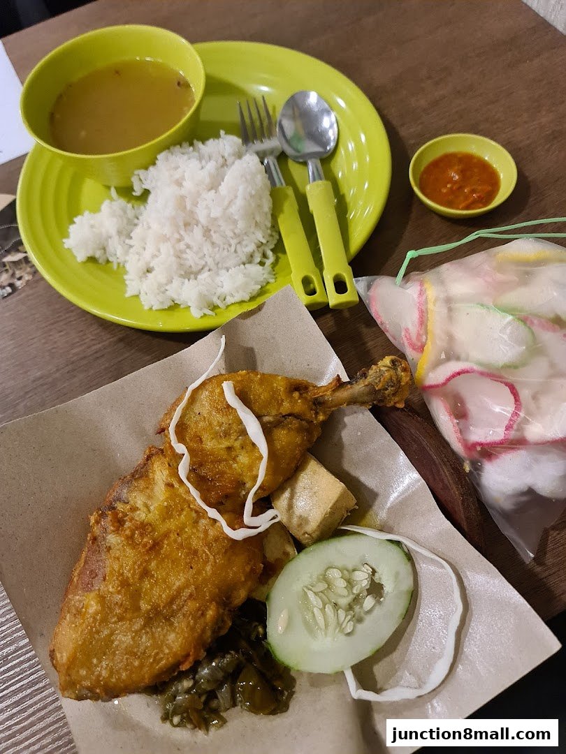 A delicious plate of fried chicken with rice, soup, chili sauce, and crackers.