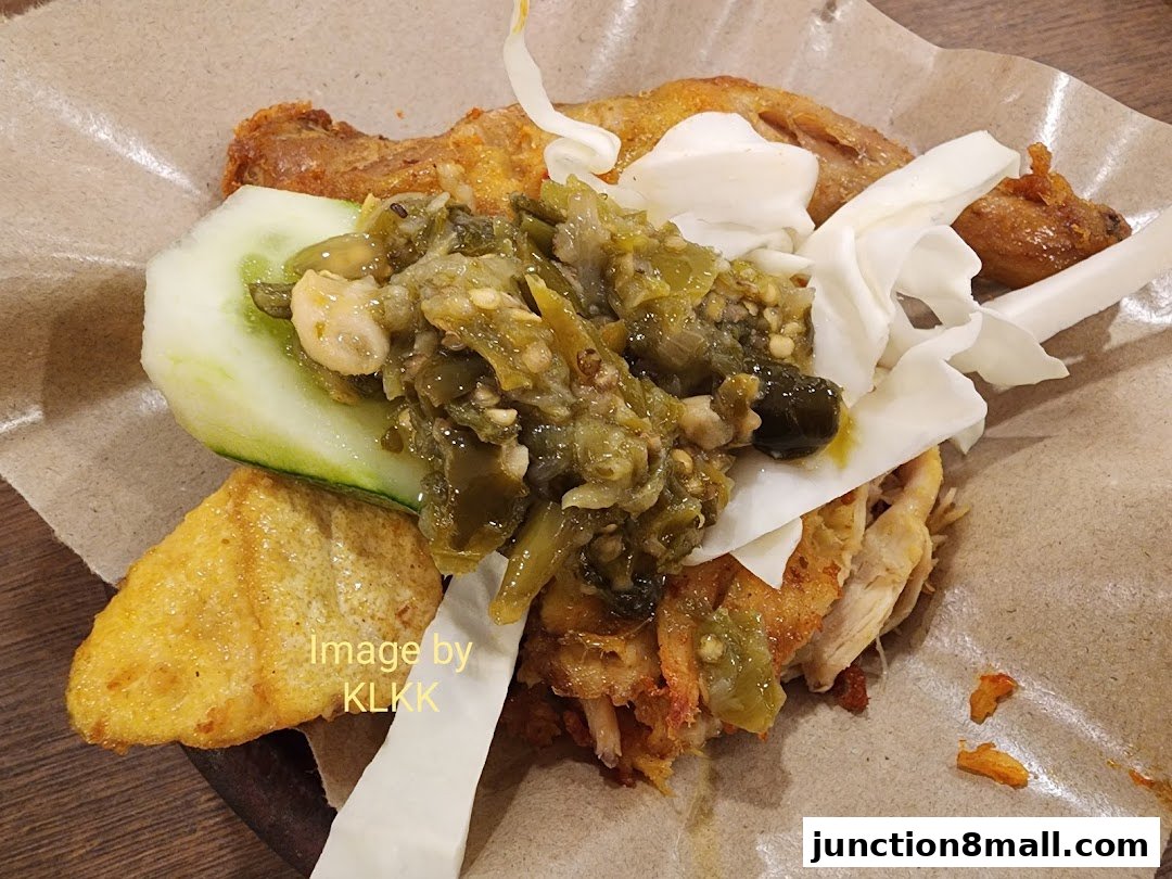 A close-up of Penyet King's signature dish featuring fried chicken, chili paste, cucumber, and tofu.