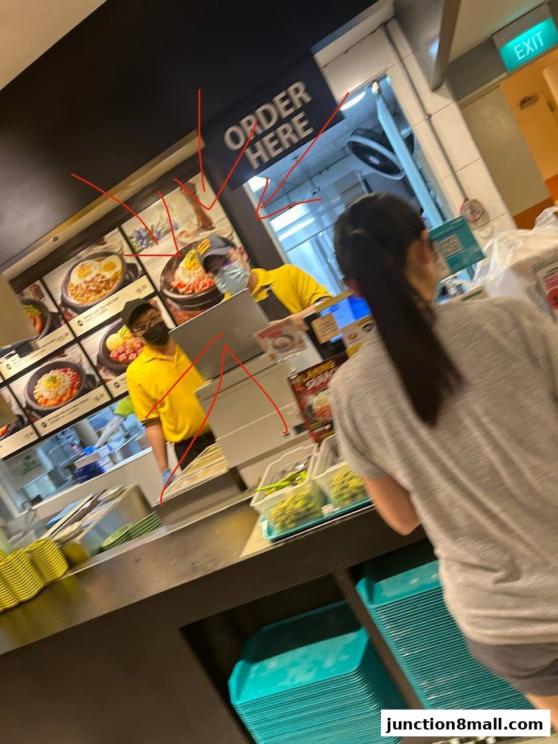 Customers ordering food at a Pepper Lunch Express counter with menu displays.