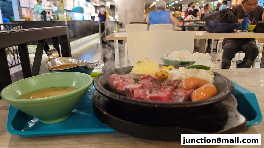 A sizzling hot plate meal with steak, sausages, mashed potatoes, and rice served at Pepper Lunch Express.