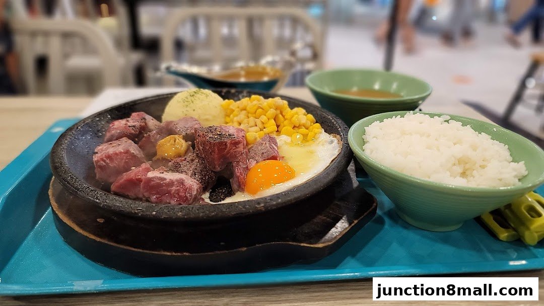 A sizzling hot plate meal with steak, corn, egg, mashed potatoes, and rice.