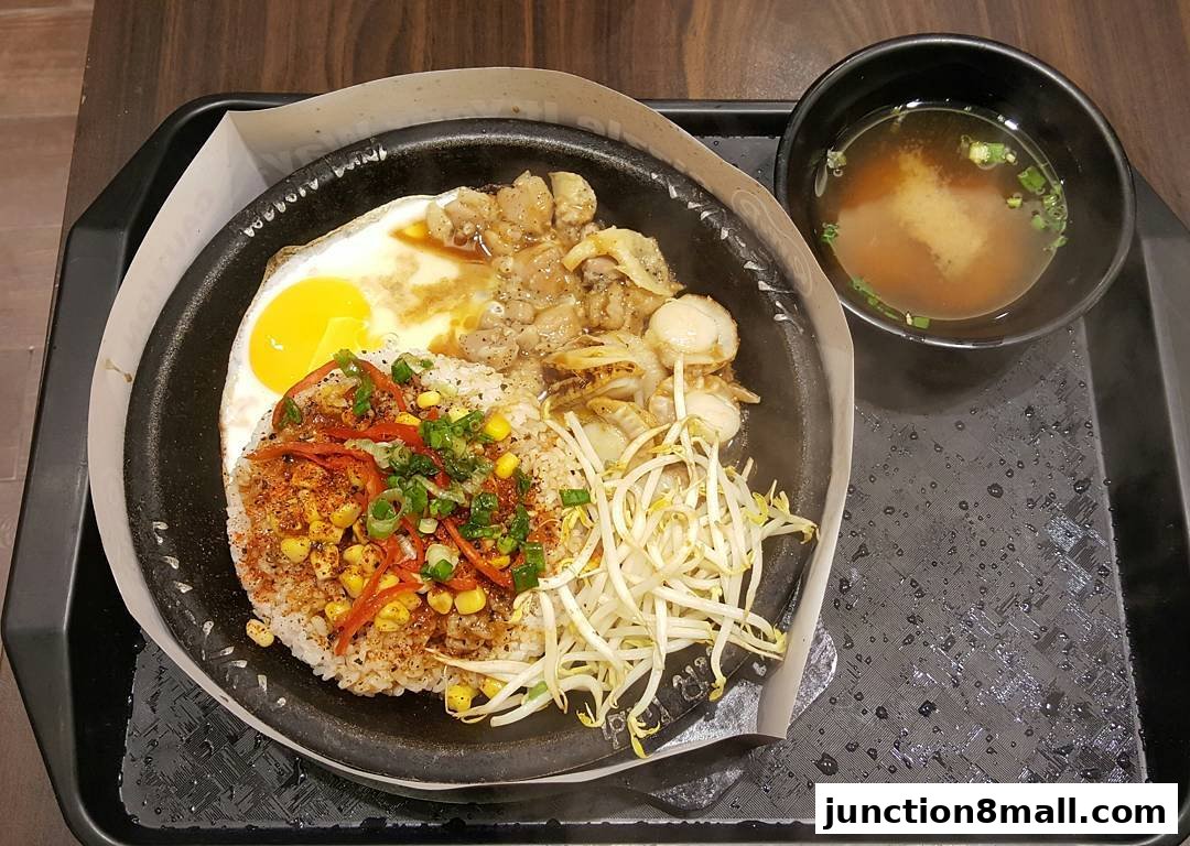 A sizzling hot plate meal with rice, egg, meat, scallops, and bean sprouts, served with miso soup.