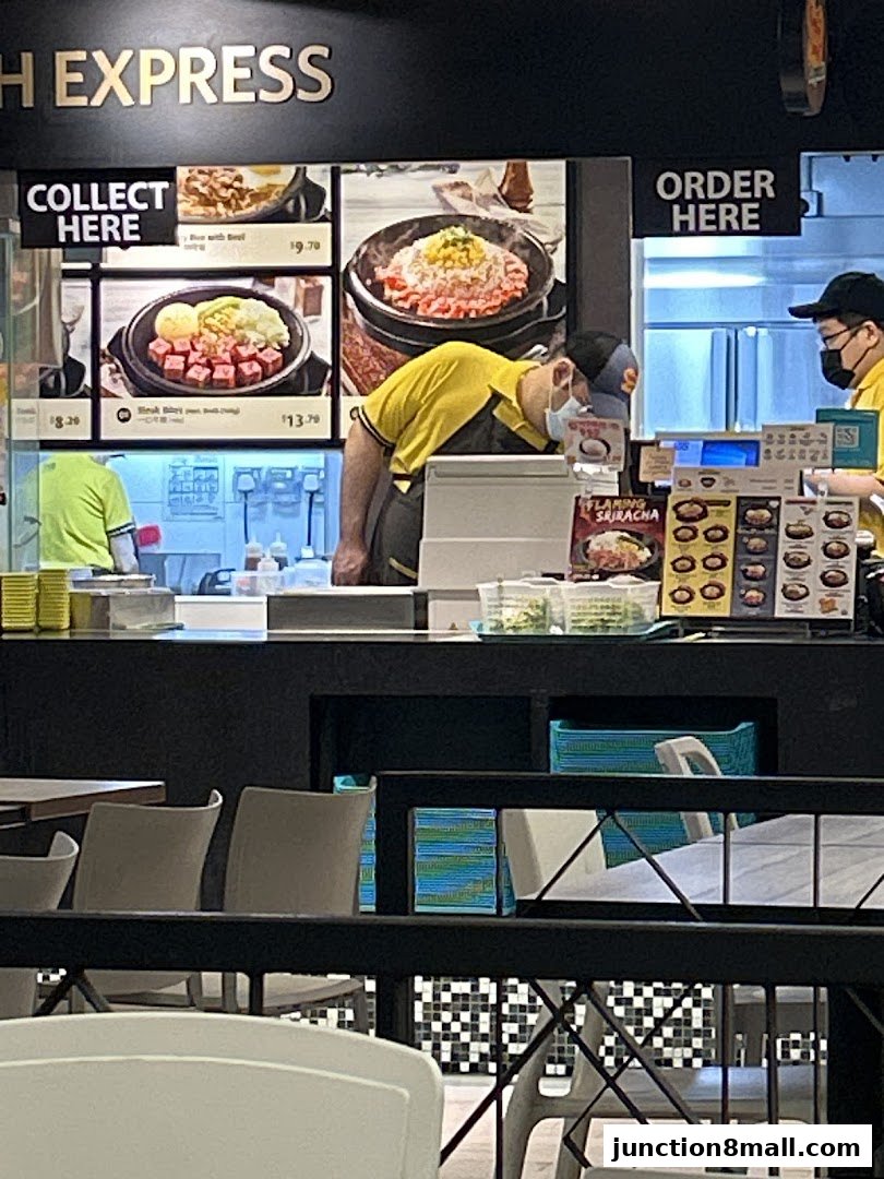 Staff members working at Pepper Lunch Express counter with menu displays and food items.