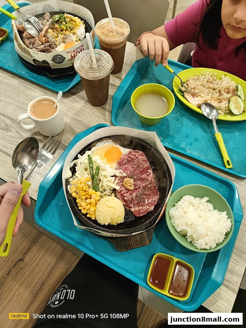 A table laden with sizzling hot plate meals, drinks, and a side of rice.