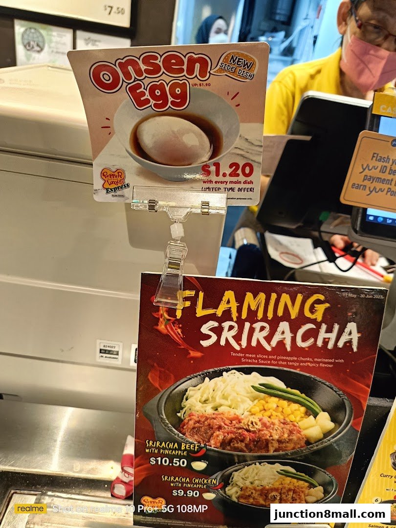 A close-up of Pepper Lunch Express menu items, featuring Onsen Egg and Flaming Sriracha dishes.