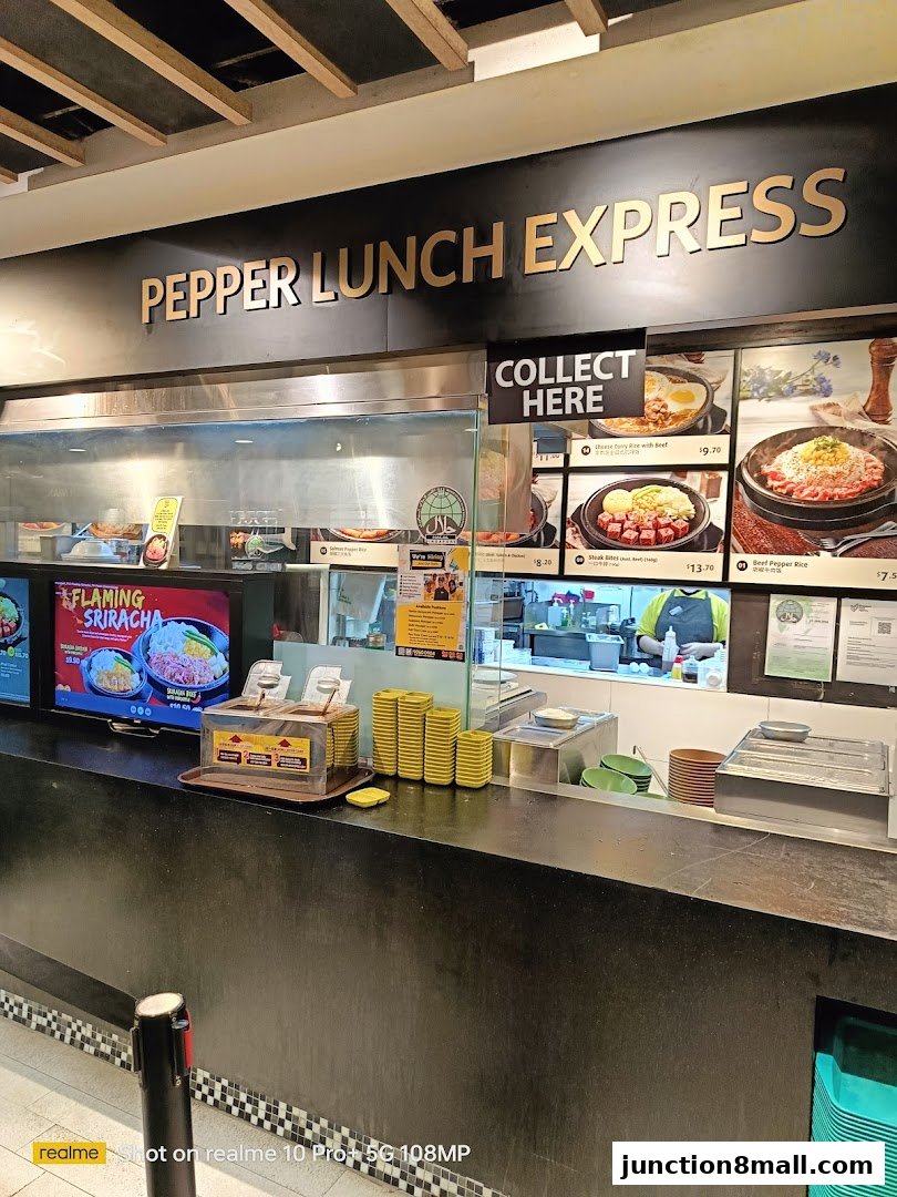 The counter and signage of a Pepper Lunch Express outlet, showcasing menu items and a collection point.