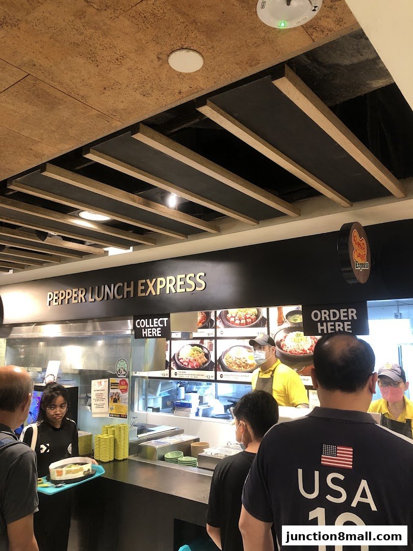 Customers queue at Pepper Lunch Express, a fast-casual restaurant with a visible order counter.
