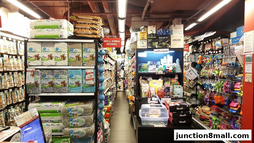 Aisle view of a pet store with shelves stocked with pet food, bedding, and toys.