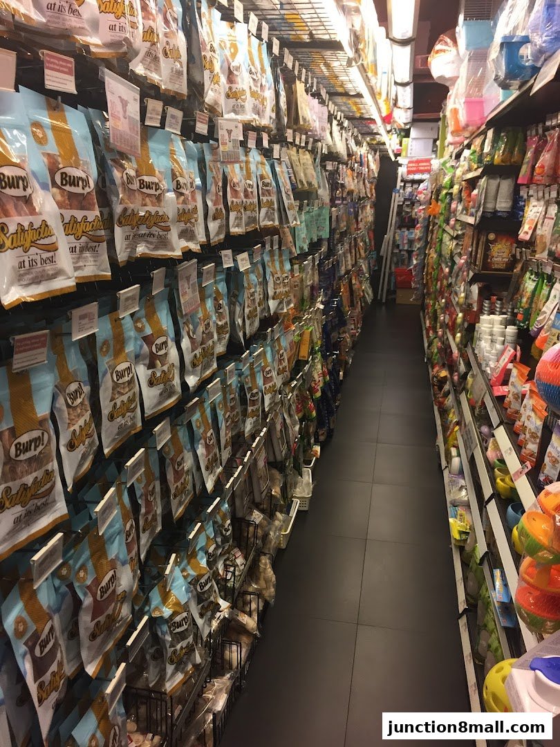 Aisle of a pet store with shelves stocked with various pet food and supplies.