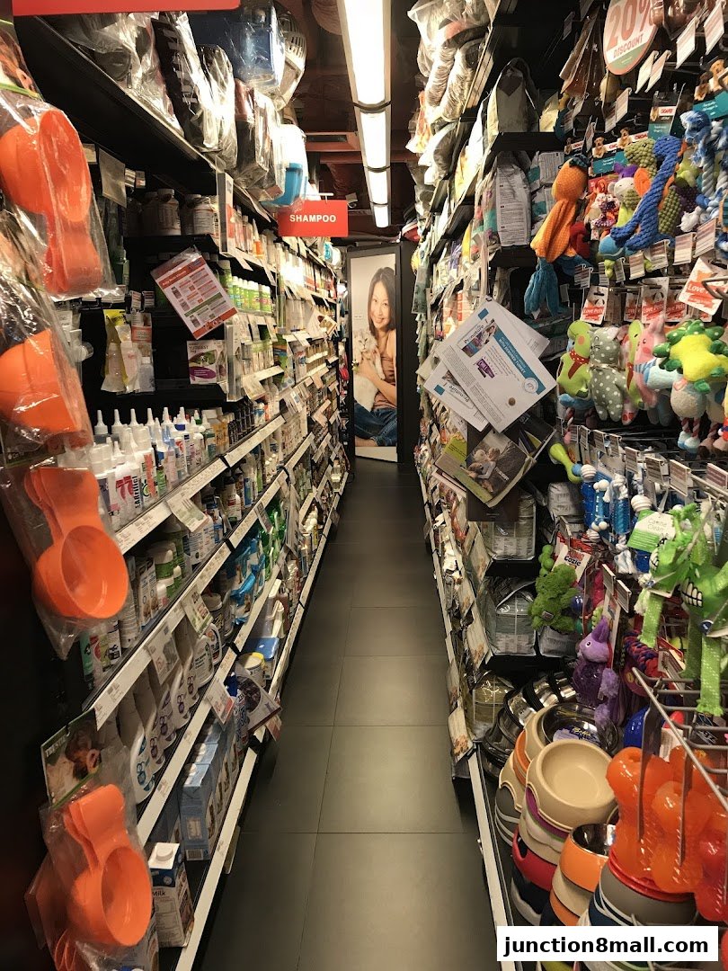 Aisle of a pet supply store with shelves stocked with pet food, toys, and accessories.