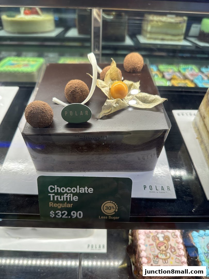 A close-up of a chocolate truffle cake with cocoa powder dusted truffles and a physalis.