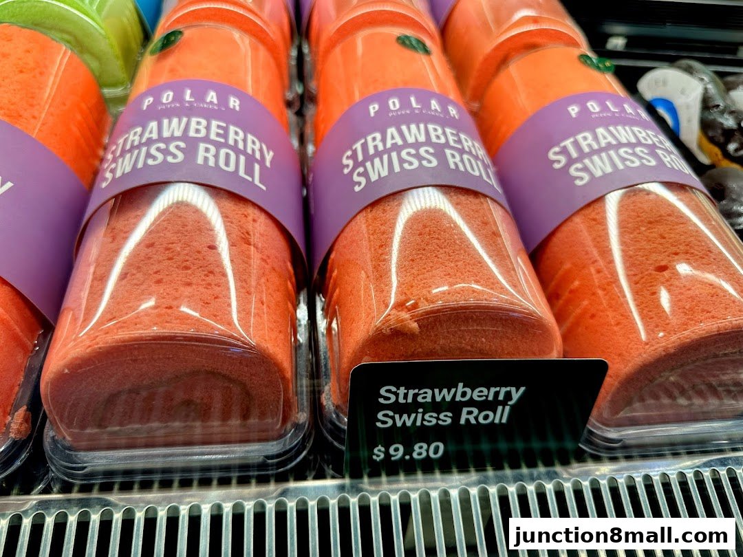 Close-up of several individually packaged strawberry swiss rolls on a display shelf.