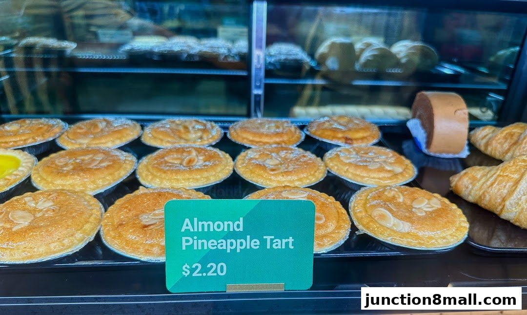 A display case filled with freshly baked almond pineapple tarts and croissants.