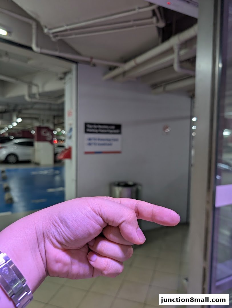 A hand points towards a shop entrance with a sign visible in the background.